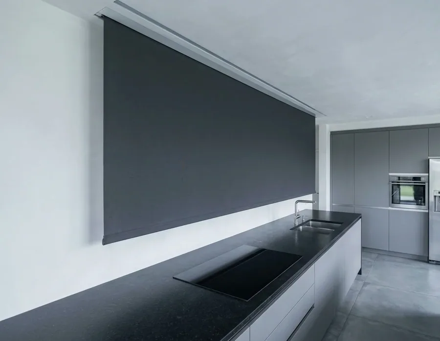 A concealed blind dropping from a slim recessed slot in the ceiling, no headrail or brackets visible